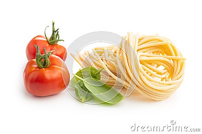 Italian pasta nest, tomato and basil leaves. Uncooked spaghetti nest Stock Photo