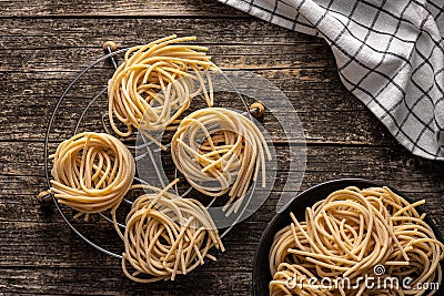 Italian pasta nest. Uncooked spaghetti nest on old wooden table Stock Photo