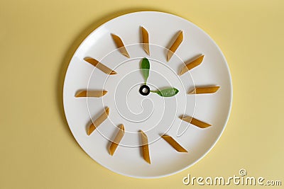 Italian pasta time. Italian penne integral and basil leaves on a white plate on a yellow background. Editorial Stock Photo