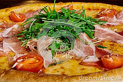 Italian pizza with ham, tomatoes and herbs on a wooden table ï¿½lose up Stock Photo