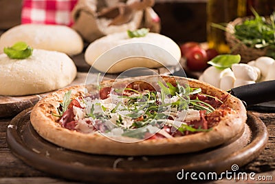 Italian Pizza with rocket salad on wooden table Stock Photo