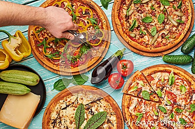 Italian pizza set at blue wooden background. chef cuts pizza. italian cuisine. gourmet pizza collection Stock Photo