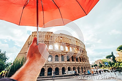 Italian Roma capital city Tourist enjoying a ancient Colosseum or Coliseum ruins out of red umbrella during a autumnal rainy day Stock Photo