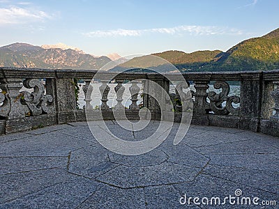 Italian stone balustrade illuminated by sun rays and water in the background Stock Photo