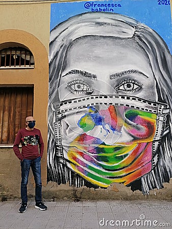 Italian street art graffiti mural woman face in medical mask. Stornara, Puglia, Italy Editorial Stock Photo