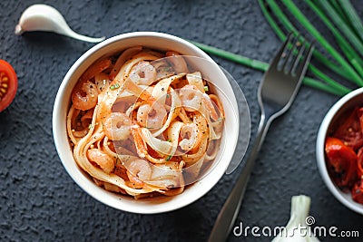 Italian tagliatelle pasta with shrimps and tomato sauce on dark background. Stock Photo