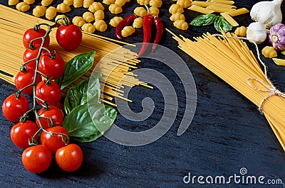 Italian traditional food, spices and ingredients for cooking: basil leaves, cherry tomatoes, garlic, chili pepper, pasta Stock Photo