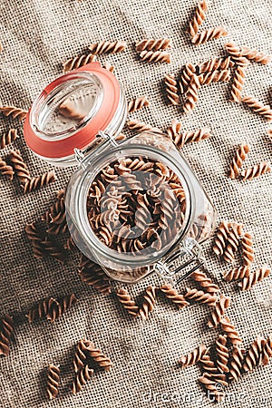 Italian unprepared pasta in a glass jar in the kitchen - fusilli Stock Photo