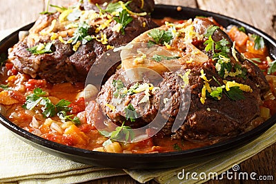 Italian veal steak Ossobuco alla Milanese with gremolata and spicy sauce closeup. horizontal Stock Photo