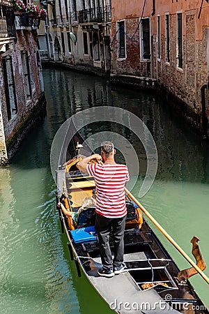 Italy, Venice, Gondolier navigating a gondola near San Moise on a canal Editorial Stock Photo