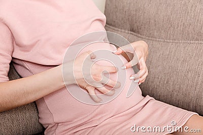Itching woman is pregnant sitting on sofa at the home Skin problems and pores in teenagers Stock Photo