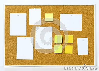 Items pinned to a cork message board with wood frame. Yellow stick notes. Stock Photo