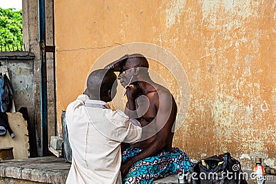 Itinerant barber under the Marina bridges Lagos Nigeria West Africa Editorial Stock Photo