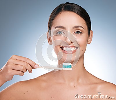 Its always better to believe. Portrait of a young beautiful woman brushing her teeth against a blue background. Stock Photo