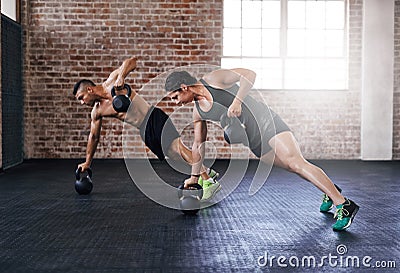 Its a display of absolute power. Full length shot of two young athletes working out in the gym. Stock Photo