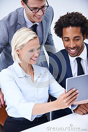 Its easy as 1, 2, 3...three colleagues looking at a digital tablet. Stock Photo