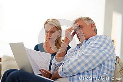 Its going to be a tough month. a mature couple looking stressed out while doing their budget at home. Stock Photo