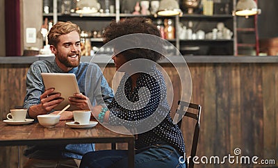 Its so good catching up with you. a young couple using a digital tablet together on a coffee date. Stock Photo