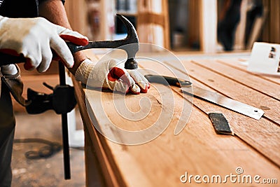 Its hammer time. an unrecognizable carpenter hammering nails on wood inside a workshop. Stock Photo