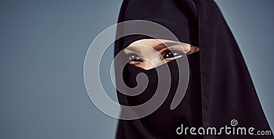 Its in her eyes. Studio shot of a young arabic woman wearing a burka against a gray background. Stock Photo