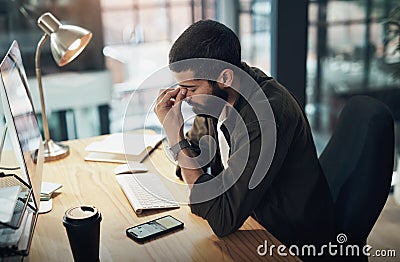 Its not all fun and games being a go getter. a young businessman feeling stressed while working late at night in a Stock Photo
