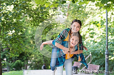 Its summer be free and happy. Energetic kids have fun piggybacking in park. Playing games outdoors. Childhood friends Stock Photo