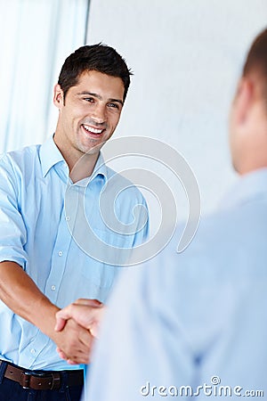 Ive got the best handshake in Hollywood. Shot of a handsome young man shaking hands with a colleague in the office. Stock Photo