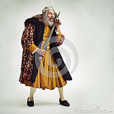 Ive an owie. Studio shot of a richly garbed king licking a cut on his finger from his sword. Stock Photo