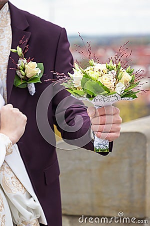 Ivory and green wedding bouquet of roses and carnation flowers in the hand of the groom Stock Photo