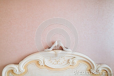 Ivory wedding women`s shoes stand on bedhead close to wall. Stock Photo