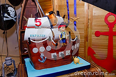 Boy birthday cake in shape of sea ship with captain mastic figure. Inscription reads Kirill is 5 years old Editorial Stock Photo