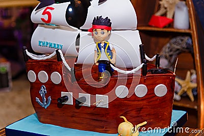 Boy birthday cake in shape of sea ship with captain mastic figure. Inscription reads Kirill is 5 years old Editorial Stock Photo