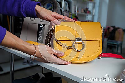 Izmail, Ukraine. May 2021. Female hands holding yellow rounded pouch, clutch with chain handle, Guess brand handbag Editorial Stock Photo