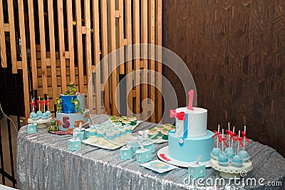 Festive candy bar for 1 and 5 years old boys birthday party. Cake with red number 1 and butterfly bow on shirt. Blue cakepops Editorial Stock Photo