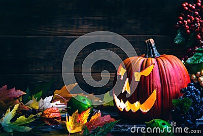 Jack o lanterns Halloween pumpkin face on wooden background and autumn leafs Stock Photo
