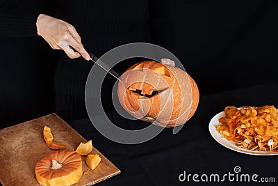 Jack`s Halloween pumpkin. Girl`s hand with a knife cutting an orange pumpkin Stock Photo