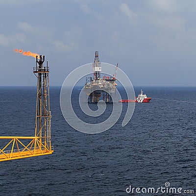 Jack up drilling rig, flare boom, and crew boat Stock Photo