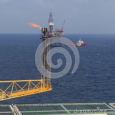 Jack up drilling rig, flare boom, and crew boat Stock Photo