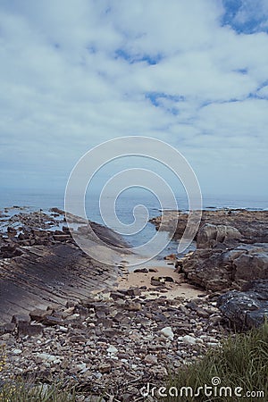 Rocky jagged Scottish coast beach under bright blue summer sky Stock Photo