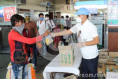 Distribution of food items and water at railway station to Indian migrant laborers leaving the city due to covid-19 pandemic. Editorial Stock Photo