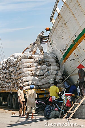 Jakarta, Indonesia - July 13, 2009: unskilled workers loading sacks from a truck onto a wooden transport vessel Editorial Stock Photo