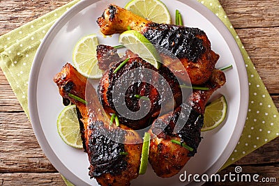 Jamaican food: jerk chicken drumstick with lime closeup on a plate. horizontal top view from above Stock Photo
