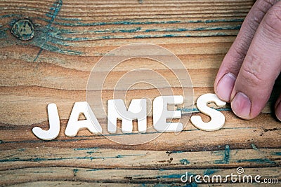 JAMES. Name of men and boys. White letters of the alphabet on a wooden background Stock Photo