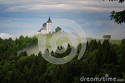 Jamnik church on a hillside in the spring, foggy weather at sunset in Slovenia, Europe. Mountain landscape shortly after spring ra Stock Photo