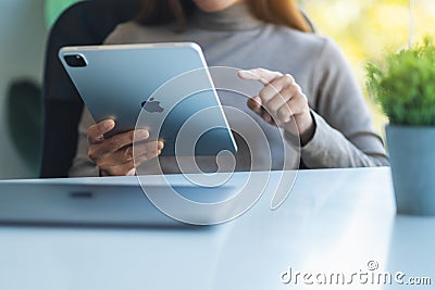 Jan 5th 2021 : A woman using Apple New Ipad Pro 2020 digital tablet with Apple MacBook Pro laptop computer on wooden Editorial Stock Photo