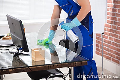 Janitor Cleaning Desk With Cloth In Office Stock Photo