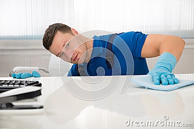 Janitor Cleaning Desk With Sponge At Office Stock Photo