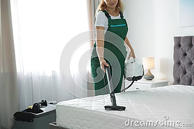 Janitor cleaning mattress with professional equipment in bedroom Stock Photo