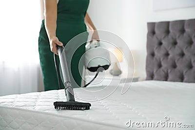 Janitor cleaning mattress with professional equipment in bedroom Stock Photo