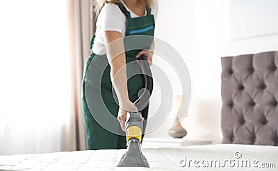 Janitor cleaning mattress with professional equipment in bedroom, Stock Photo